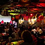 A group gathered at Full Sail's Treehouse, guests sitting down and the hosts on stage. The room is dimly lit and decorated with red paper lanterns for the Lunar New Year.